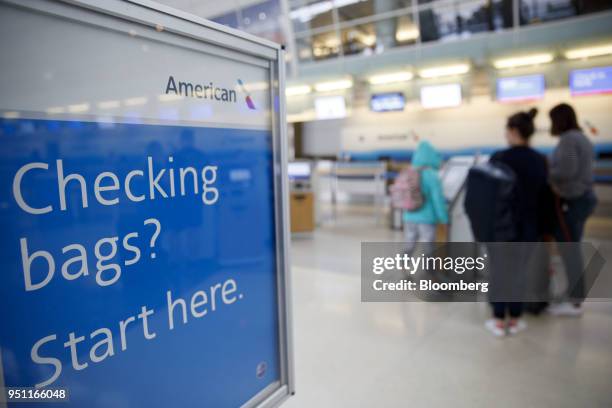 American Airlines Group Inc. Signage is displayed as travelers check-in for flights at Dallas-Fort Worth International Airport in Grapevine, Texas,...