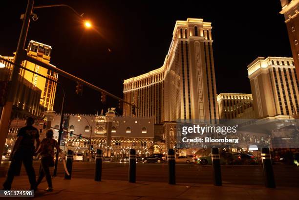 Pedestrians pass in front of the Las Vegas Sands Corp. Venetian resort illuminated at night in Las Vegas, Nevada, U.S., on Tuesday, April 24, 2018....