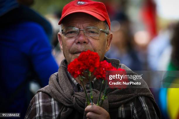 Demonstrator holds a red carnation as he marches through downtown Lisbon on April 25, 2018 during a rally to celebrate the 44th anniversary of the...