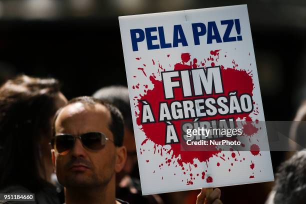 Man holds a placard reading 'for the peace! End to agressions to Siria!' in central Lisbon on April 25, 2018 during a rally to celebrate the 44th...
