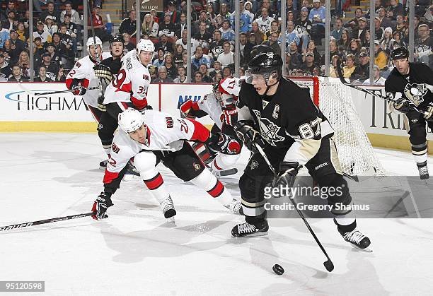 Sidney Crosby of the Pittsburgh Penguins looks to pass in front of the defense of Chris Kelly of the Ottawa Senators on December 23, 2009 at Mellon...