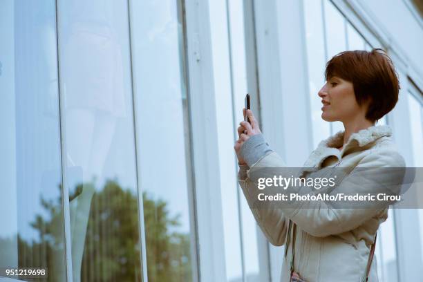 woman photographing shop window with smartphone - désir photos et images de collection