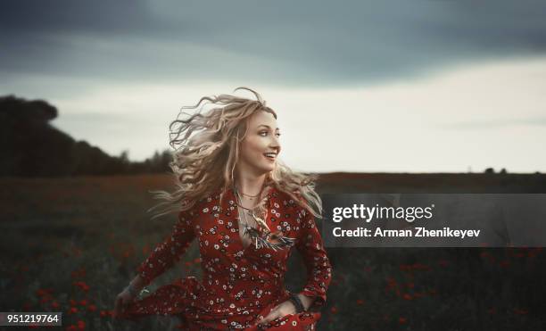 dancing hippie woman in poppy field - arman zhenikeyev stock-fotos und bilder