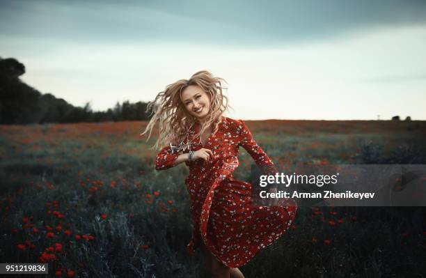 dancing hippie woman in poppy field - arman zhenikeyev stock-fotos und bilder