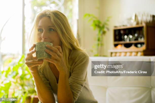 mature woman drinking coffee at home - woman drinking tea stock pictures, royalty-free photos & images