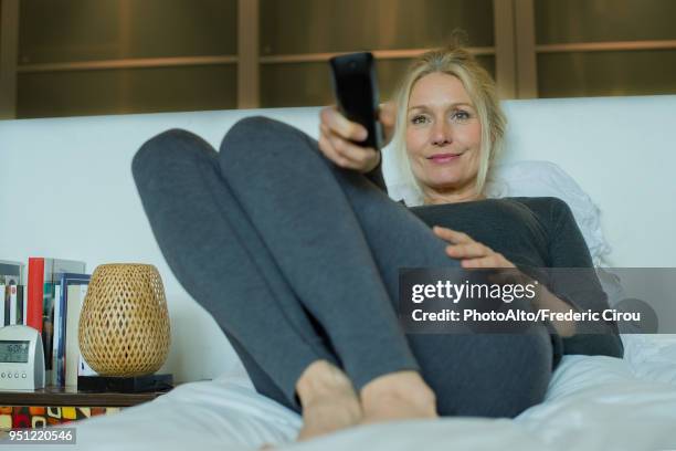 mature woman watching tv in bed - donne bionde scalze foto e immagini stock