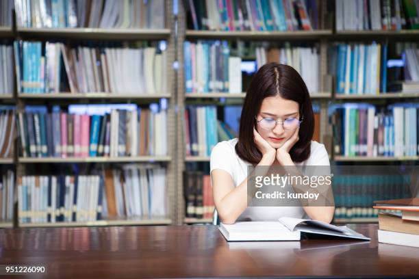 student reading a book in library. - literature student stock pictures, royalty-free photos & images