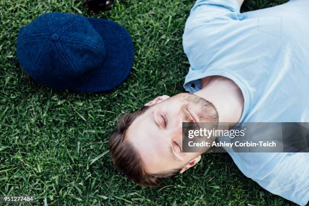 man sleeping on grass - man sleeping with cap stock pictures, royalty-free photos & images