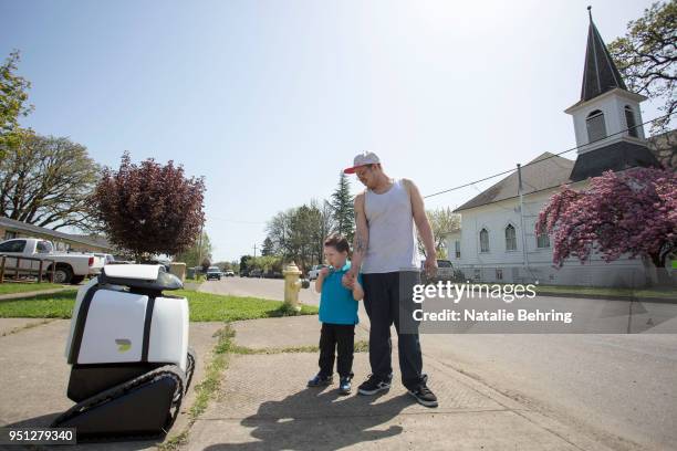 Little boy and his father meet delivery robot 'DAX' as it makes a delivery April 25, 2018 in Philomath, Oregon. Joseph Sullivan, the inventor of DAX...