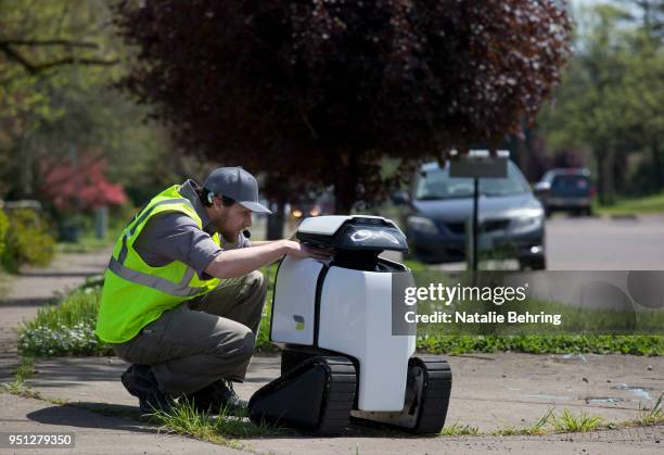 Technician makes an adjustment to delivery robot 'DAX' as it makes a delivery April 25, 2018 in Philomath, Oregon. Joseph Sullivan, the inventor of...