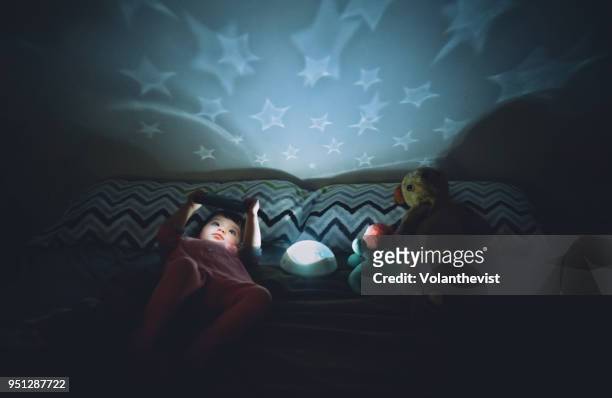 baby girl watching cartoons on mobile at night in bed - chambre bébé photos et images de collection