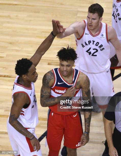 Toronto Raptors guard DeMar DeRozan and Toronto Raptors center Jakob Poeltl high five over Washington Wizards forward Kelly Oubre Jr. As the Toronto...