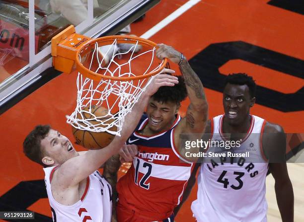 Washington Wizards forward Kelly Oubre Jr. Dunks on Toronto Raptors center Jakob Poeltl as Pascal Siakam looks on as the Toronto Raptors play game...