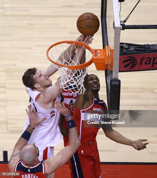 Toronto Raptors center Jakob Poeltl and Washington Wizards guard Bradley Beal reach for a rebound as the Toronto Raptors play game five of their...