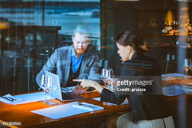mann und frau, die eine diskussion in der mittagszeit in einem edlen restaurant - business lunch stock-fotos und bilder