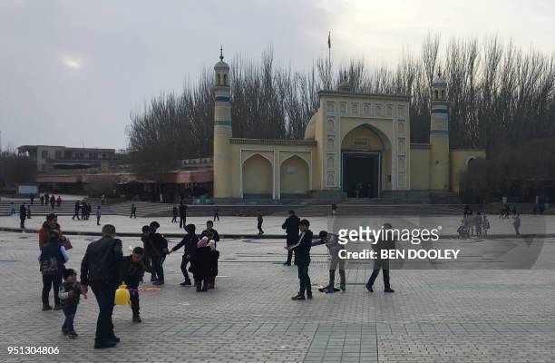 This photo taken on February 18, 2018 shows children playing outside the Id-kah mosque in Kashgar, in China's western Xinjiang region. - The...