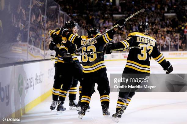 David Pastrnak of the Boston Bruins celebrates with Brad Marchand and Patrice Bergeron after scoring a goal against the Toronto Maple Leafs during...