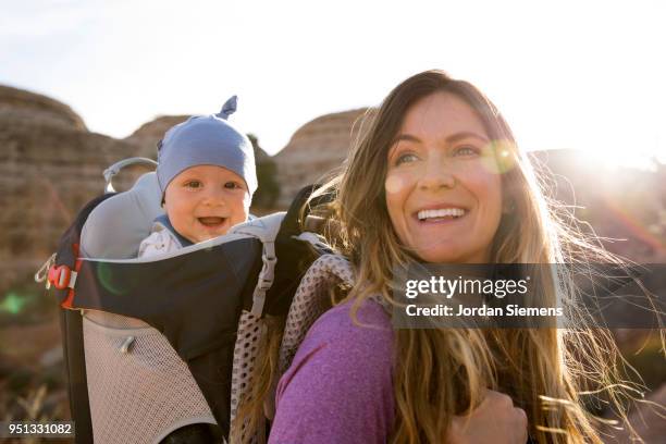 a young mom hiking with her baby - baby bag stock-fotos und bilder