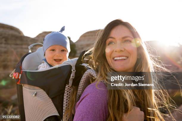 a young mom hiking with her baby - baby bag stockfoto's en -beelden