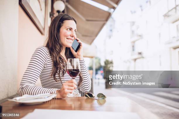 young woman drinking red wine at restaurant, using smart phone - no drinking stock pictures, royalty-free photos & images