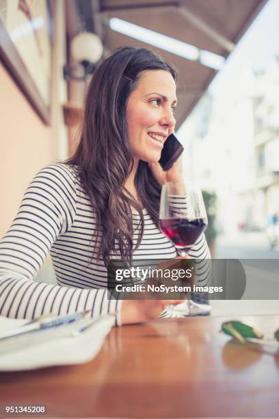 young woman drinking red wine at restaurant, using smart phone - no drinking stock pictures, royalty-free photos & images