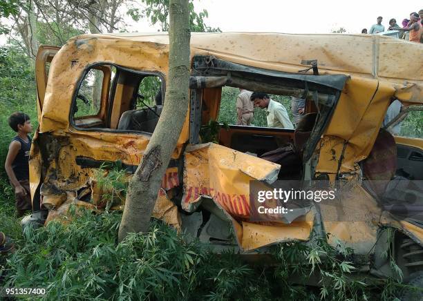 Onlookers gather around the mangled remains of a school bus after it was hit by a train in Kushinagar district in India's Uttar Pradesh state on...