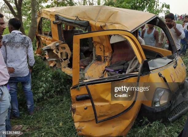 Onlookers gather around the mangled remains of a school bus after it was hit by a train in Kushinagar district in India's Uttar Pradesh state on...