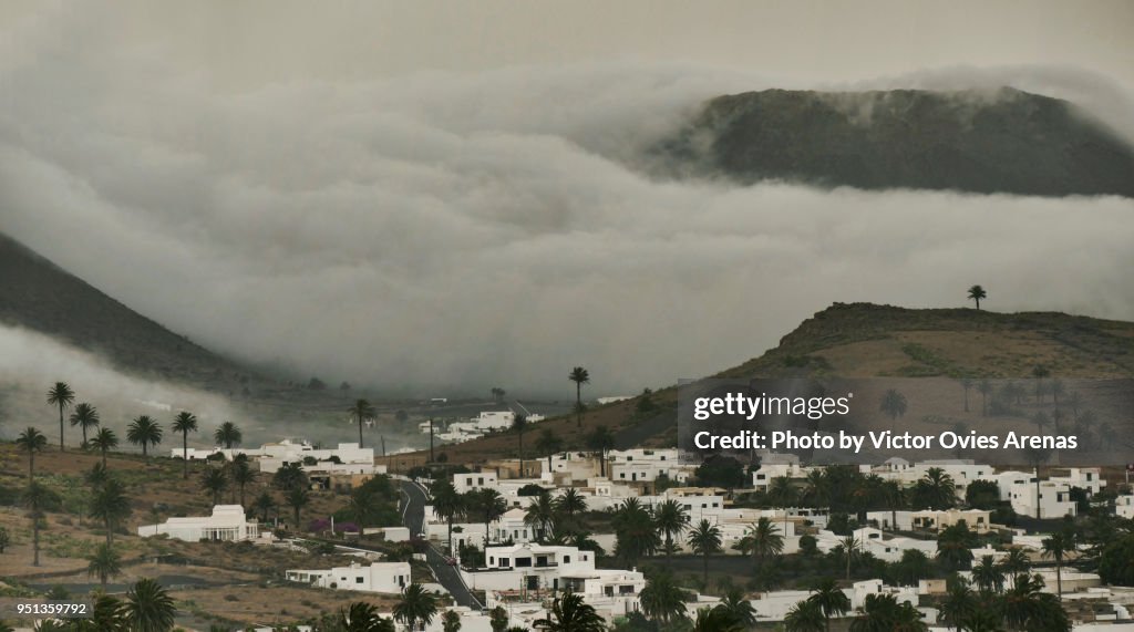 Tumultuous clouds flowing downhill behind the village of Haria in Lanzarote, Canary Islands, Spain