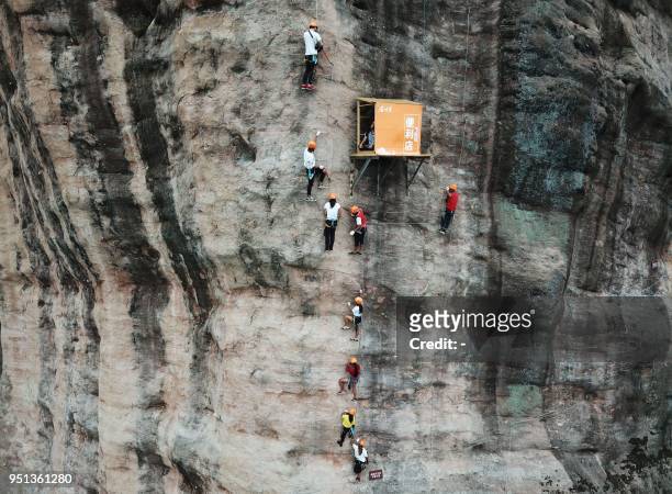 This photo taken on April 25, 2018 shows people rock climbing past a 100-meter-high convenience store on a cliff in Pingjiang in China's central...
