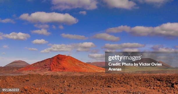 the red mountain (montaña colorada volcano) volcanic landscape in lanzarote exceptionally showing a thin green layer of grass after the rain in lanzarote, canary islands - montaña stock pictures, royalty-free photos & images