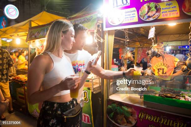 tourists looking at crabs at krabi town night market thailand - krabi stock pictures, royalty-free photos & images