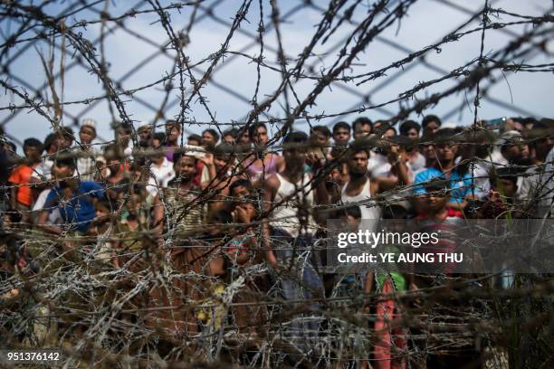 This picture taken from Maungdaw district, Myanmar's Rakhine state on April 25, 2018 shows Rohingya refugees gathering behind a barbed-wire fence in...