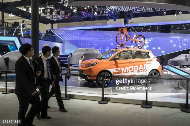 Attendees walk past a China FAW Group Corp. SiTech DEV1 electric vehicle on display at the Beijing International Automotive Exhibition in Beijing,...