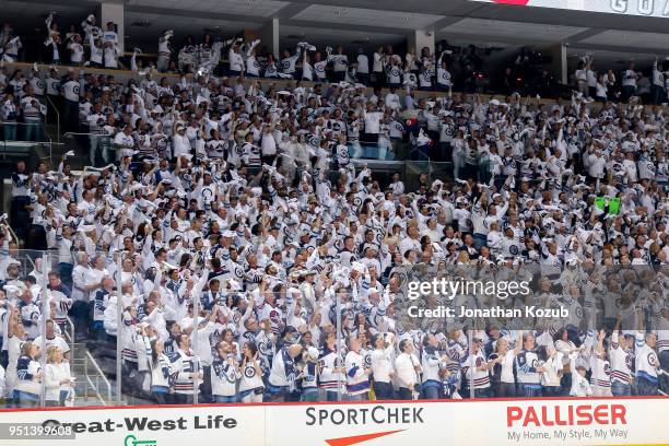 Winnipeg Jets fans clad all in white stand and cheer after a first period goal against the Minnesota Wild in Game Five of the Western Conference...