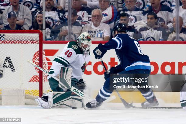 Goaltender Devan Dubnyk of the Minnesota Wild makes a pad save on Jacob Trouba of the Winnipeg Jets during first period action in Game Five of the...