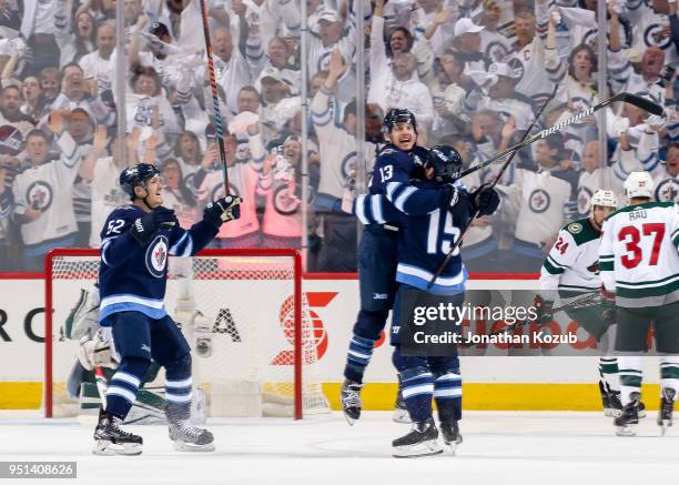 Brandon Tanev of the Winnipeg Jets leaps into the arms of teammate Matt Hendricks as he celebrates his first period goal against the Minnesota Wild...