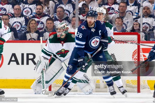 Blake Wheeler of the Winnipeg Jets battles Joel Eriksson Ek of the Minnesota Wild in front of goaltender Alex Stalock during first period action in...