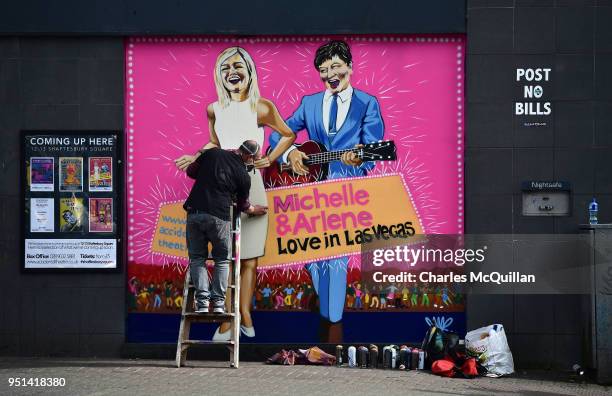 Street artist JMK finishes work on a new mural depicting DUP leader Arlene Foster and Sinn Fein northern leader Michelle O'Neill on April 26, 2018 in...