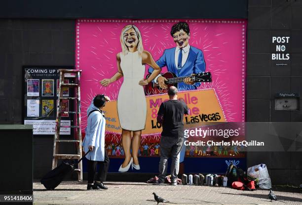 Street artist JMK finishes work on a new mural depicting DUP leader Arlene Foster and Sinn Fein northern leader Michelle O'Neill on April 26, 2018 in...