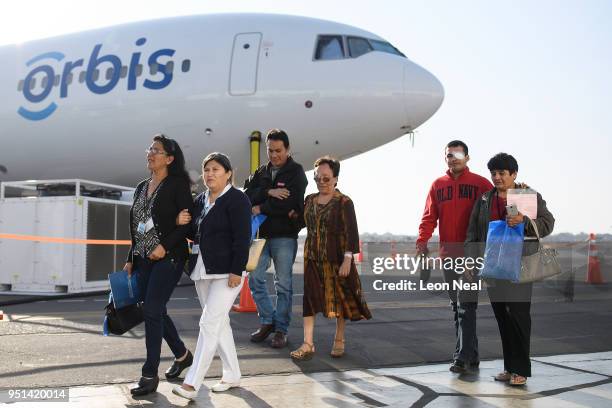 Patients are helped back through the airport terminal after having surgical procedures onboard the Orbis Flying Eye Hospital on April 17, 2018 in...