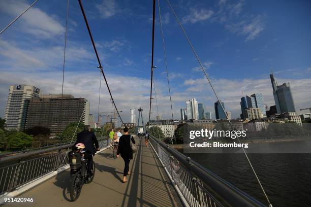 Cyclist and pedestrians pass over a bridge spanning the River Main as skyscrapers stand beyond in Frankfurt, Germany, on Wednesday, April 25, 2018....