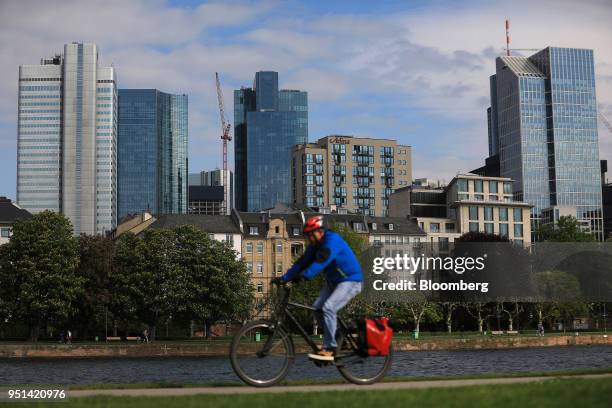 Cyclist moves alongside the River Main as skyscrapers stand beyond in Frankfurt, German, on Wednesday, April 25, 2018. About 8,000 additional jobs...