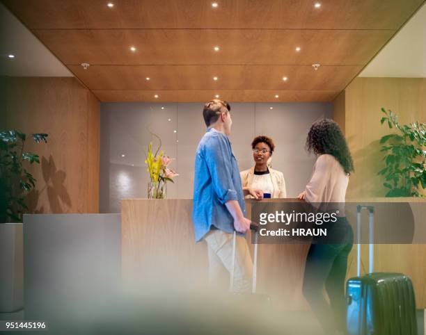 couple talking to receptionist at hotel lobby - hotel stock pictures, royalty-free photos & images
