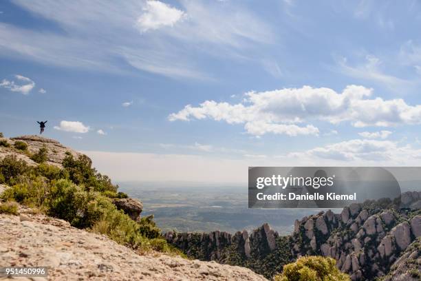 woman jumping in air by cliff in the montserrat mountains, spain - monte montserrat catalogna foto e immagini stock