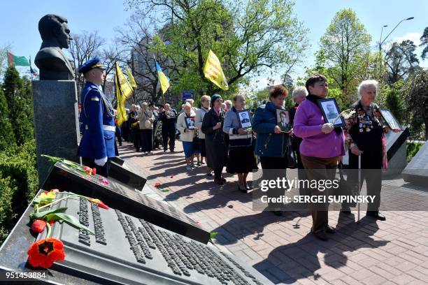 Widows carry the pictures of their late husbands, who were "liquidators" in Chernobyl, during a ceremony in tribute to the victims of the Chernobyl...