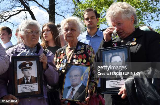 Widows react as they hold pictures of their deceased husbands, who were "liquidators" in Chernobyl, during a ceremony marking the 32d anniversary of...