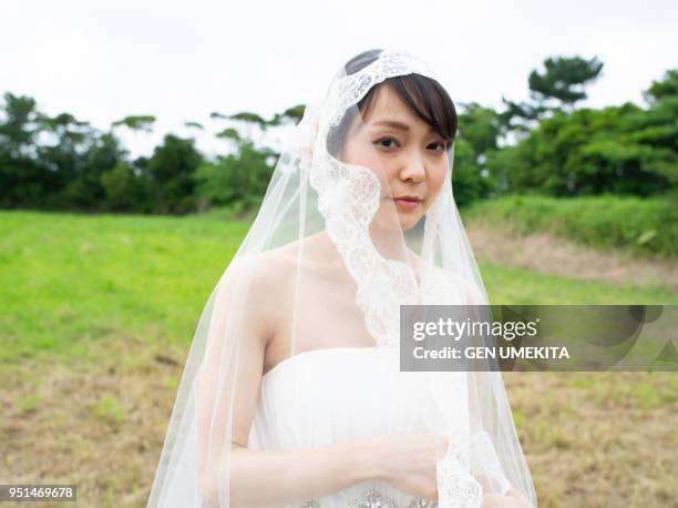 a bride walking on the meadow - 結婚式 日本 ストックフォトと画像