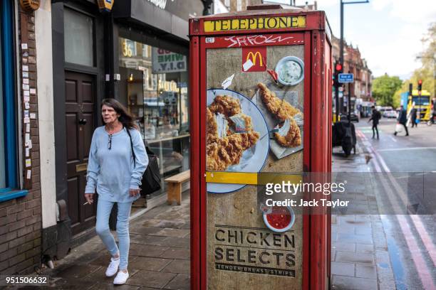 Woman walks past an advert for fast food chicken on a telephone box in Camberwell on April 26, 2018 in London, England. Party leaders have called on...