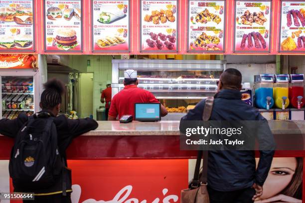Customers wait at the counter of a chicken shop in Camberwell on April 26, 2018 in London, England. Party leaders have called on the Government to...