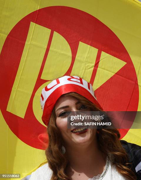 An Iraqi Kurd woman poses in front of the flag of the Kurdistan Democratic Party during an electoral rally, in Arbil, the capital of the northern...